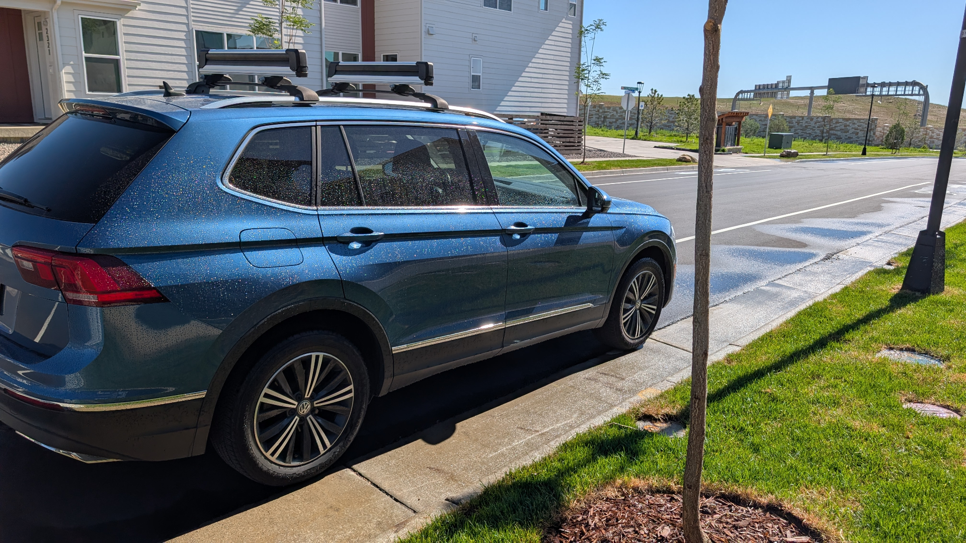 Blue VW Tiguan parked on a downtown Superior street, entire side of the car covered in sprinkler droplets minutes after the sprinklers shut off